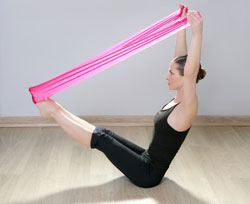 Woman sitting with arms and legs up, stretching a band from her feet to her hands