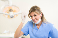 Dentist in scrubs smiling and holding a light