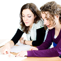 Two women looking over a notebook.