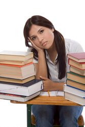 Girl looking sad sitting at her desk surrounded by books