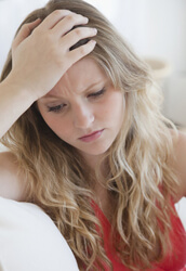 Woman looking puzzled with her hand on her forehead.