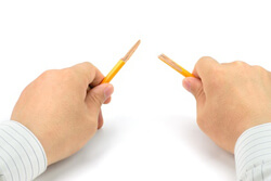 Hands holding a pencil that has been snapped in half